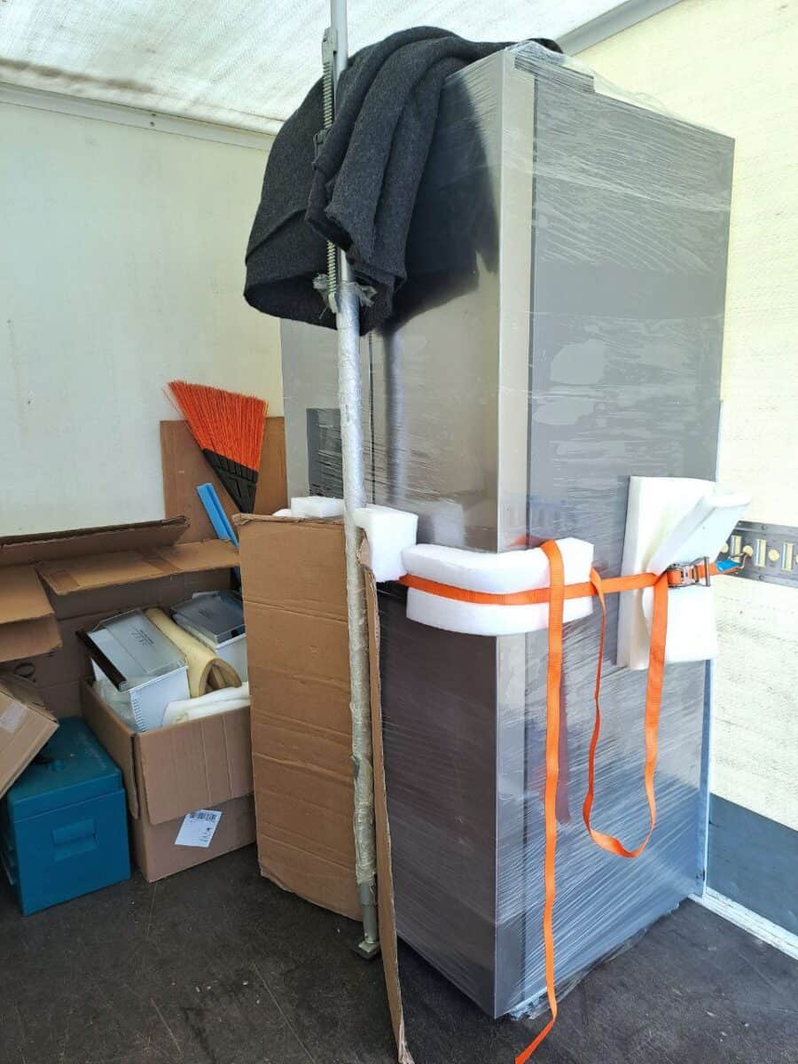 Külmkapi transport Tartus – kilesse pakitud seade kinnitatud porolooni ja rihmaga kolimisautos.