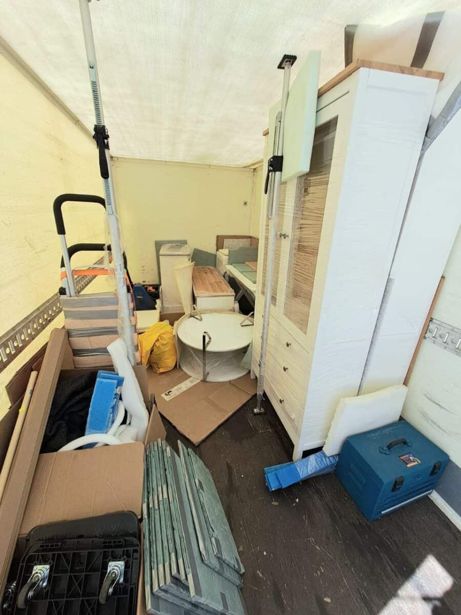 Kolimisauto Tartus – kilesse pakitud valge kapp, ümmargune lauaplaat ja kastid, koorem kinnitatud tugipostidega.