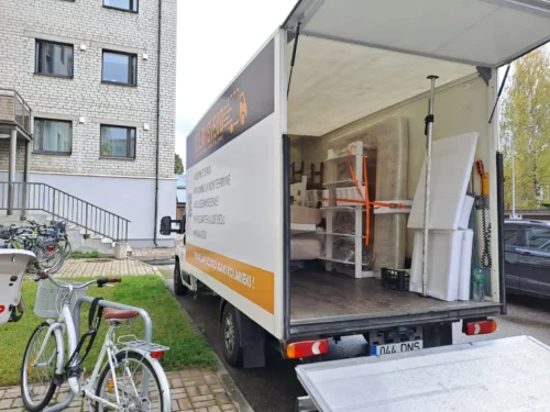 Kolimisteenus Tartus: kontorimööbel pakitud kilega, põrandal kolimisalused ja paketitarvikud.